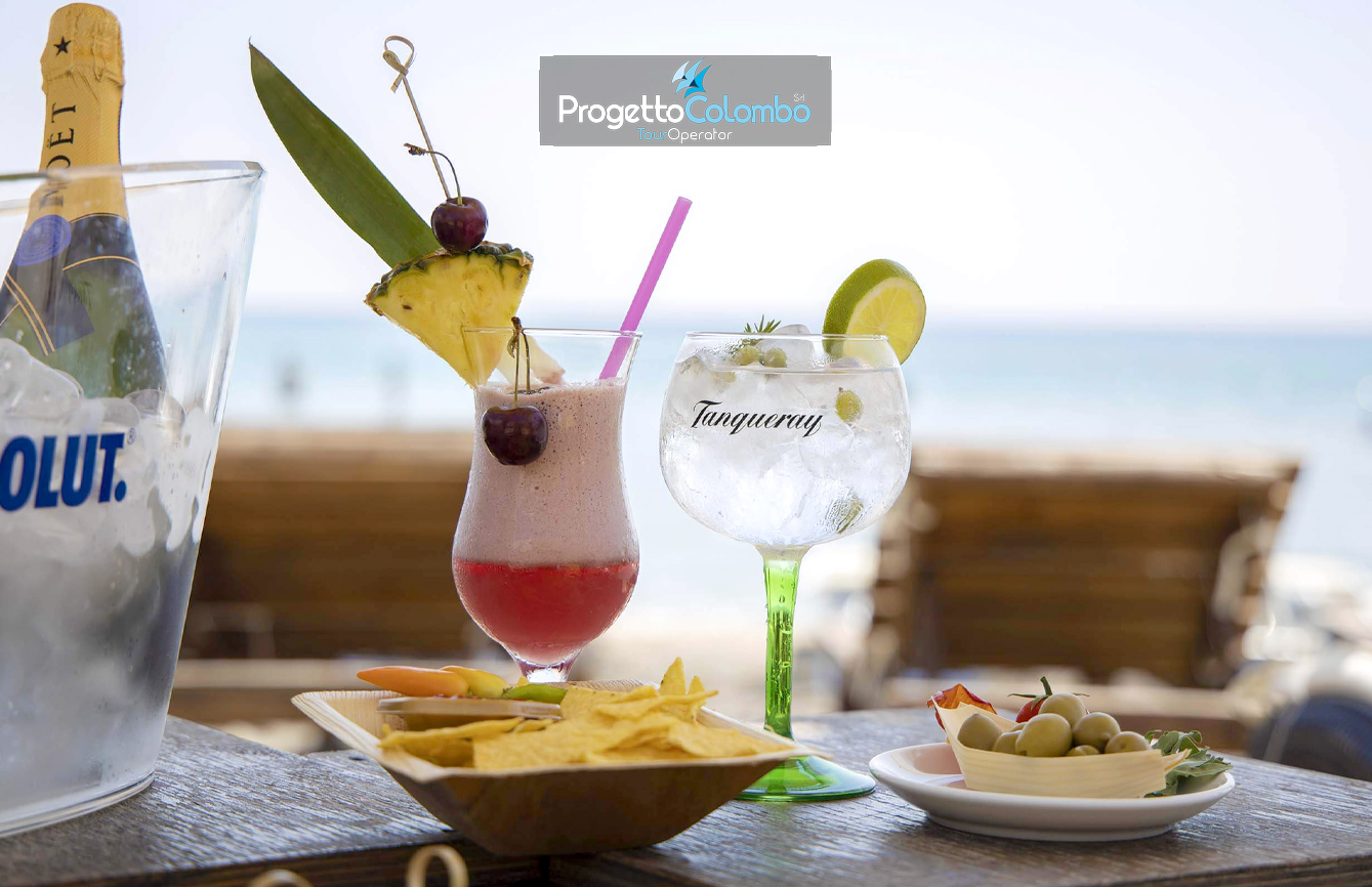 Progetto Colombo Bari, Tour Operator, Mare Italia, Voi Alimini resort, Alpitour, Bravo Club, All Inclusive, Top Club, Puglia, Salento_Bar Spiaggia 2 Spiaggia e Mare: "Spiaggia di sabbia bianca e mare cristallino del VOI Alimini Resort a Otranto, ideale per vacanze a metà settembre." Piscina: "Ampia piscina all'aperto circondata dal verde del giardino nel resort VOI Alimini in Puglia." Ristorazione: "Buffet vario e colorato nella sala ristorante del VOI Alimini Resort per gli ospiti in formula all-inclusive." Organizzazione Progetto Colombo Viaggi Bari