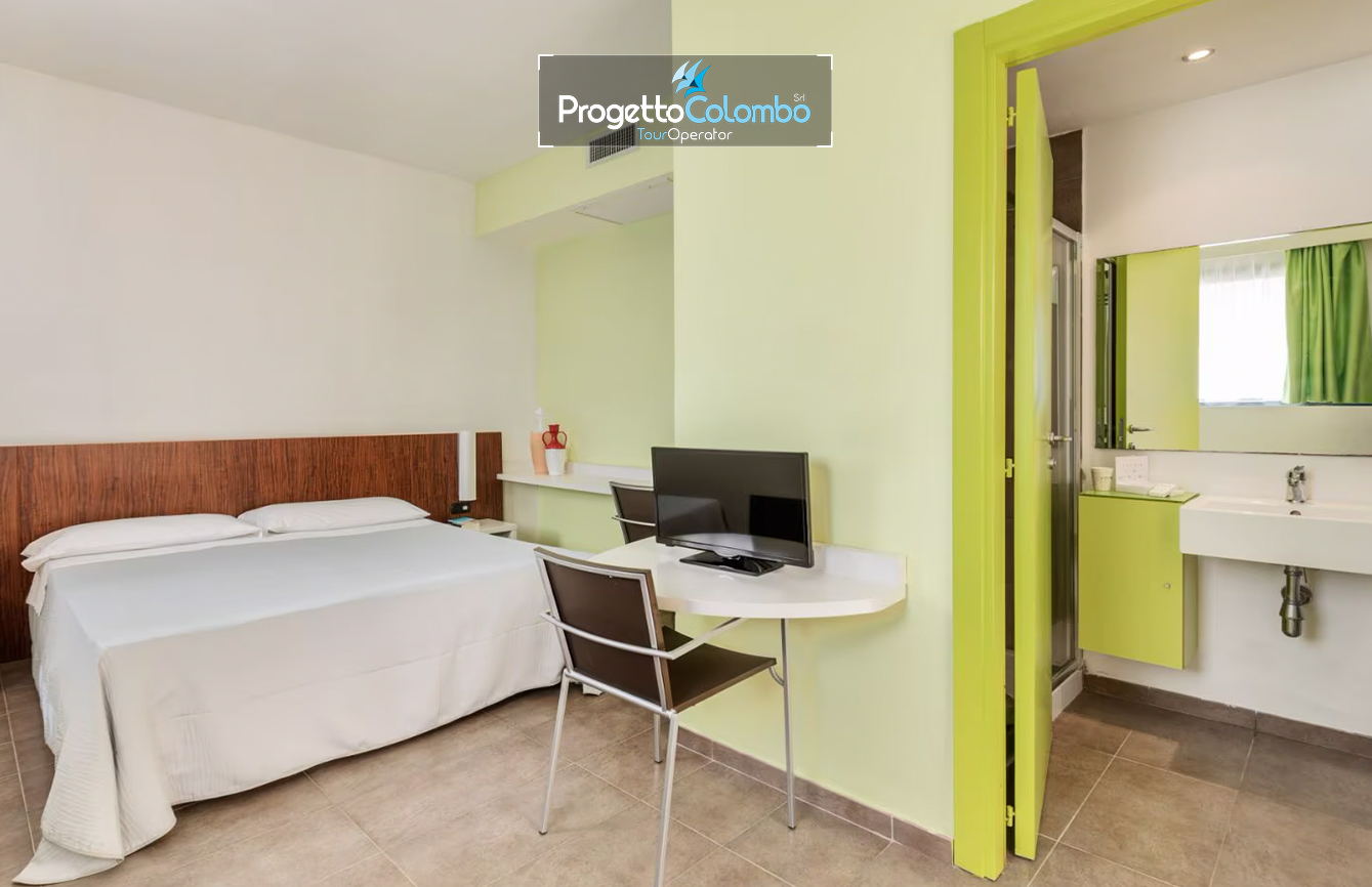 Progetto Colombo Bari, Tour Operator, Mare Italia, Voi Alimini resort, Alpitour, Bravo Club, All Inclusive, Top Club, Puglia, Salento_Camera Smart Spiaggia e Mare: "Spiaggia di sabbia bianca e mare cristallino del VOI Alimini Resort a Otranto, ideale per vacanze a metà settembre." Piscina: "Ampia piscina all'aperto circondata dal verde del giardino nel resort VOI Alimini in Puglia." Ristorazione: "Buffet vario e colorato nella sala ristorante del VOI Alimini Resort per gli ospiti in formula all-inclusive." Organizzazione Progetto Colombo Viaggi Bari